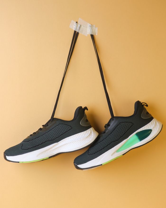 services-02 Black and white sports sneakers creatively displayed on a vibrant yellow backdrop.