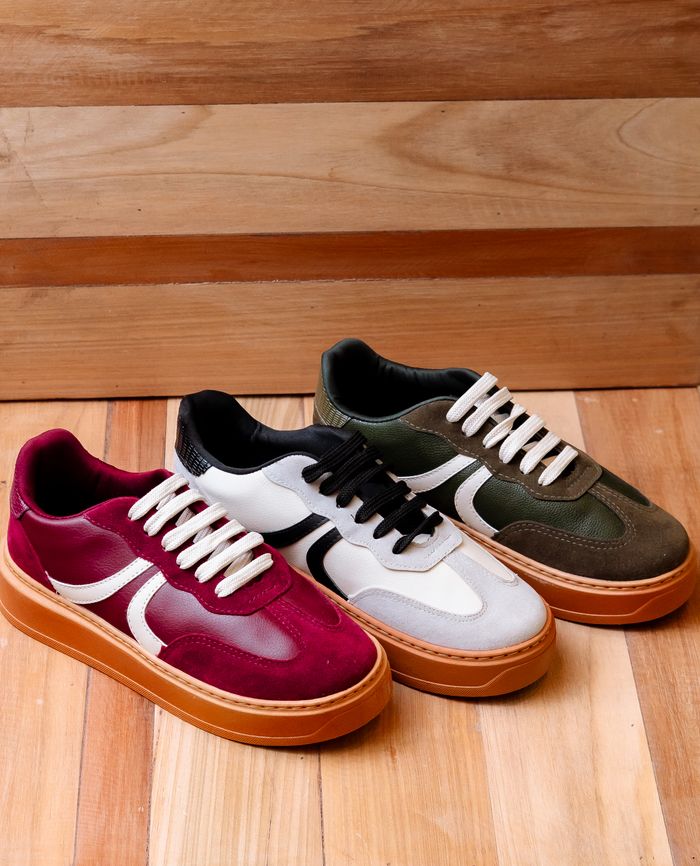 services-03 Three pairs of trendy sneakers on a wooden floor offer a stylish footwear display.