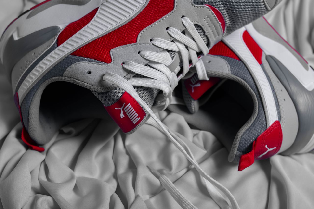 services-04 From above of modern sneakers with red elements and white shoelaces placed on crumpled fabric
