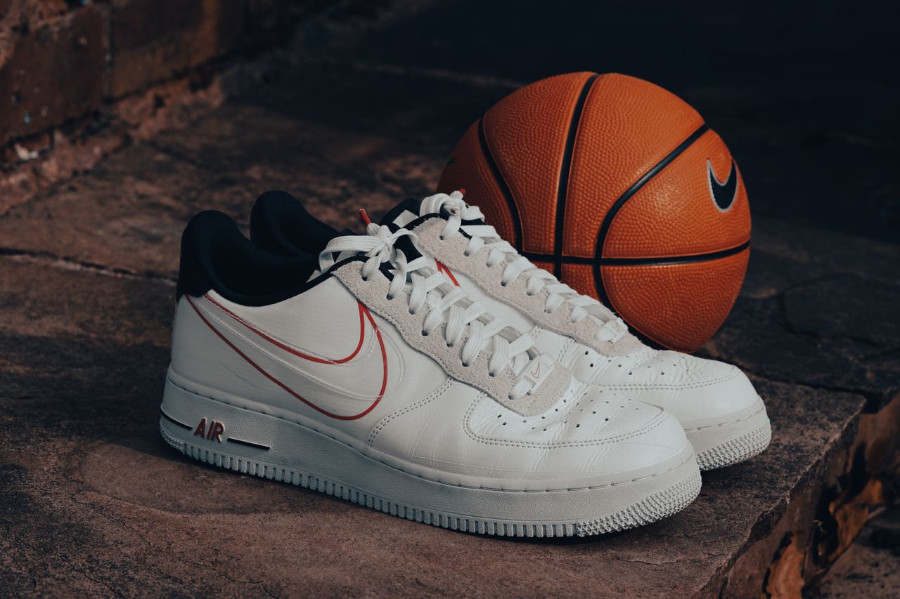 Stylish white sneakers paired with a Nike basketball on a rustic stone background.